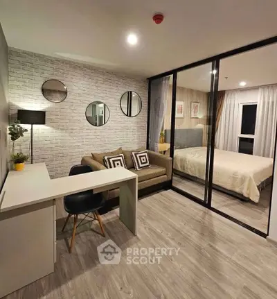 Modern studio apartment with stylish decor and cozy bedroom separated by glass partition.