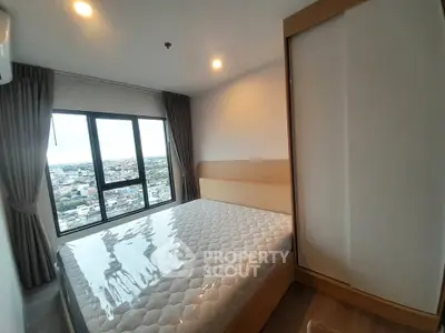 Modern bedroom with large window offering stunning city views, featuring a comfortable bed and sleek wardrobe.