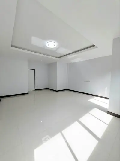 Spacious empty room with modern ceiling light and large windows