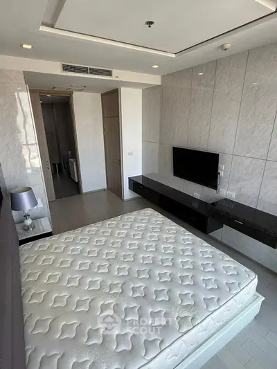 Modern bedroom with sleek design, featuring a wall-mounted TV and stylish decor.