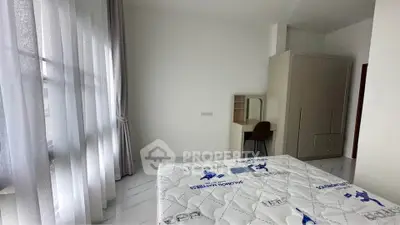Spacious bedroom with natural light and modern furnishings in a stylish apartment.