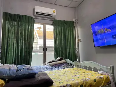 Cozy bedroom with air conditioning and wall-mounted TV, featuring green curtains and a comfortable bed.