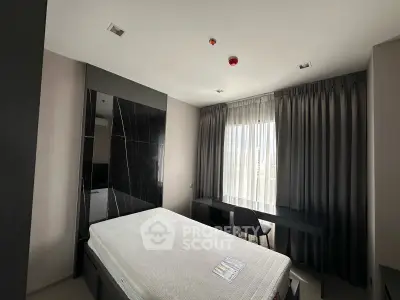 Modern bedroom with sleek design, featuring a comfortable bed and stylish desk by a large window.