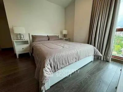 Cozy bedroom with elegant decor and large window offering natural light.