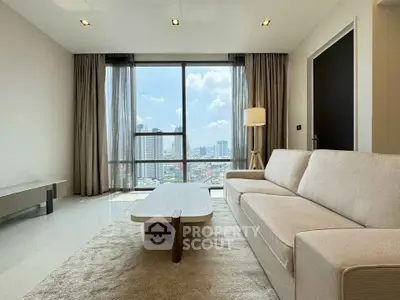 Modern living room with city view, featuring a sleek sofa and elegant decor.