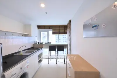 Modern kitchen with sleek design, featuring a washing machine and breakfast bar with city view.