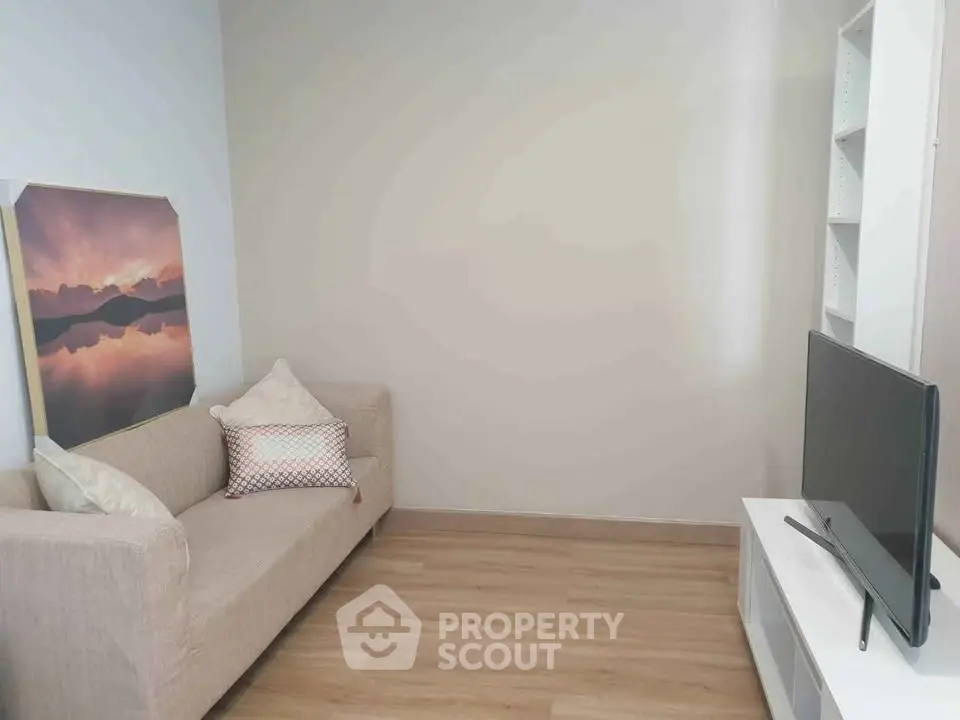Cozy living room with modern sofa and flat-screen TV, perfect for relaxation.