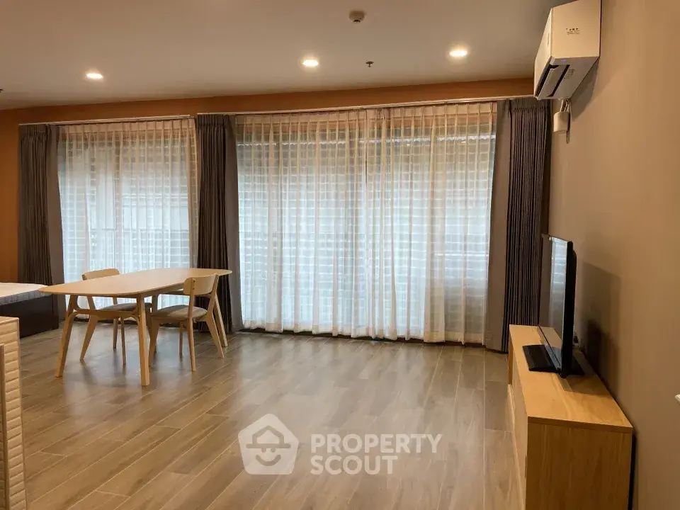 Spacious modern living room with large windows and elegant wooden flooring.