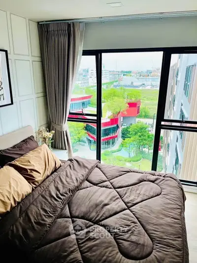 Modern bedroom with large windows offering a stunning city view, featuring elegant decor and cozy bedding.