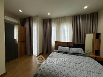 Spacious bedroom with modern decor and large windows for natural light.