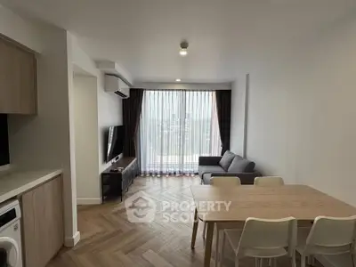 Modern living room with wooden flooring, large window, and cozy furniture in a stylish apartment.