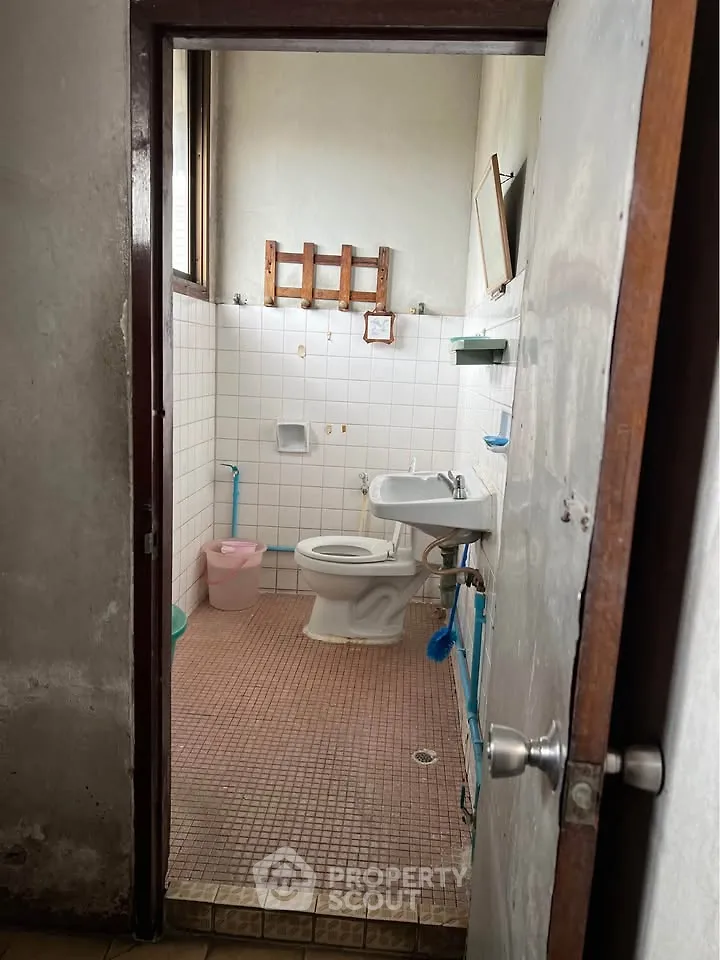 Cozy bathroom with tiled walls and floor, featuring a toilet and sink, ideal for compact living spaces.