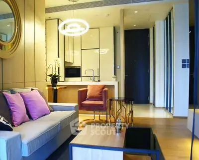 Modern living room with stylish decor and open kitchen layout, featuring elegant lighting and cozy seating.