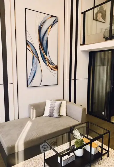 Modern living room with stylish decor and high ceiling, featuring a sleek sofa and contemporary artwork.