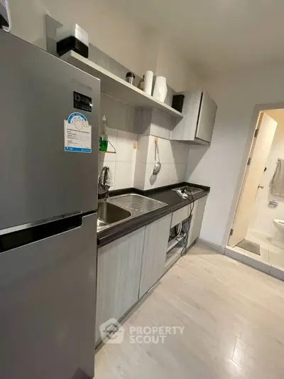 Modern kitchen with sleek cabinets and stainless steel fridge in a cozy apartment.