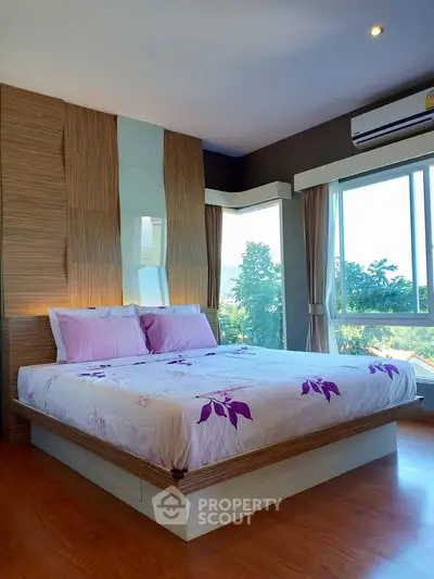 Spacious bedroom with large windows and scenic view, featuring modern decor and cozy bedding.