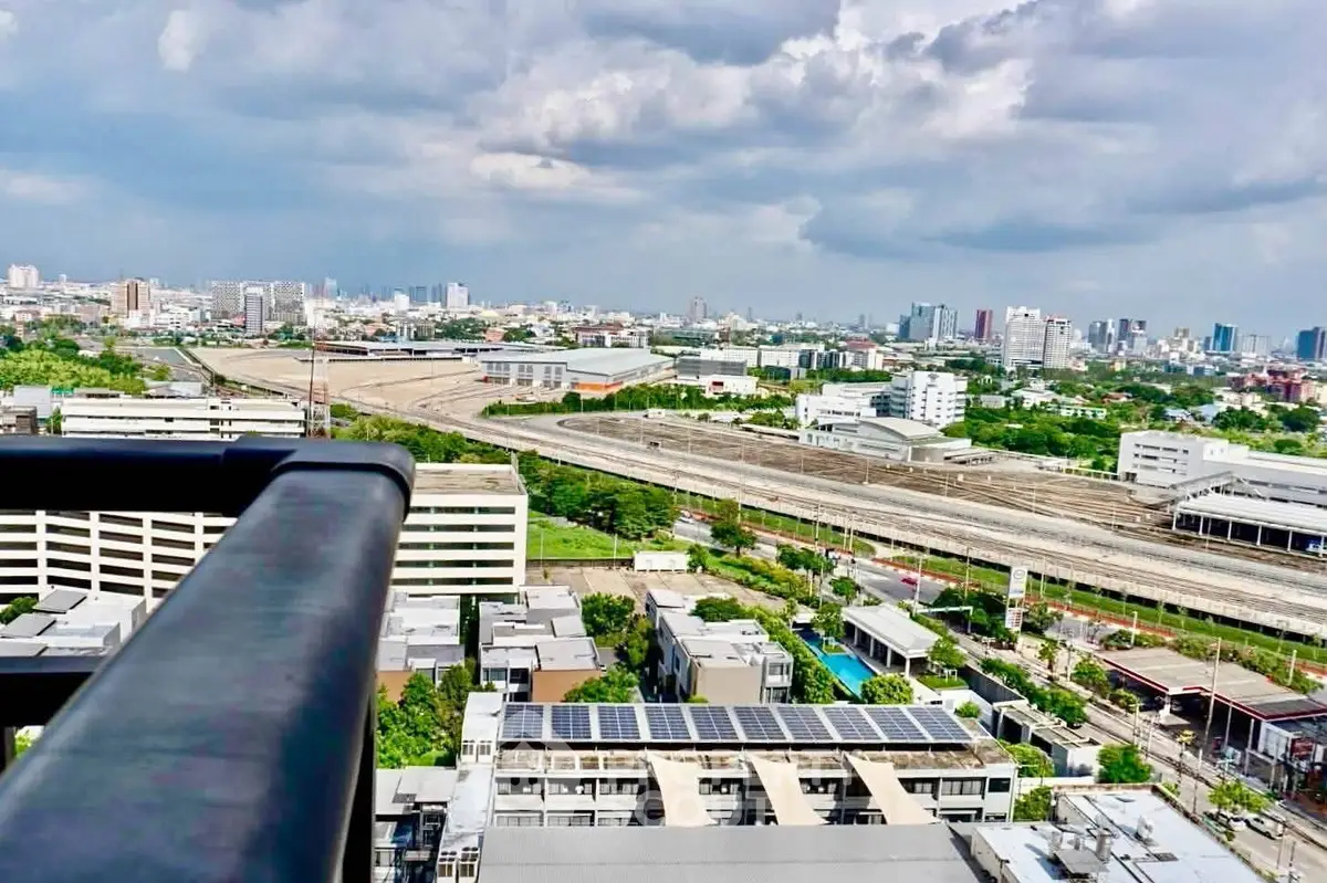 Stunning cityscape view from a high-rise balcony overlooking urban landscape and railway tracks.