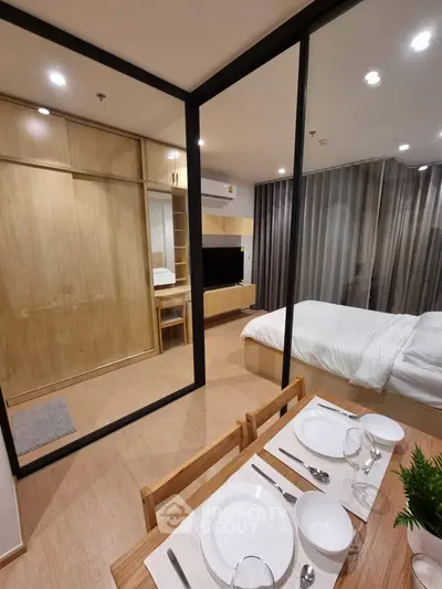 Modern studio apartment with glass partition, cozy dining area, and elegant bedroom setup.