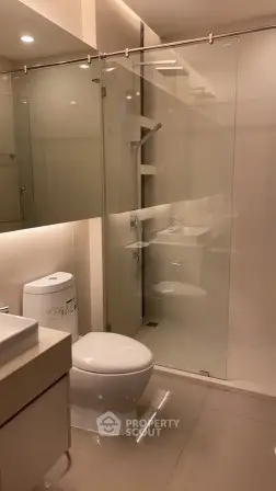 Modern bathroom with glass shower and sleek fixtures in contemporary apartment.