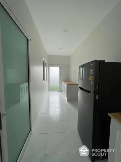 Modern kitchen with sleek design and natural light, featuring a large refrigerator and ample counter space.