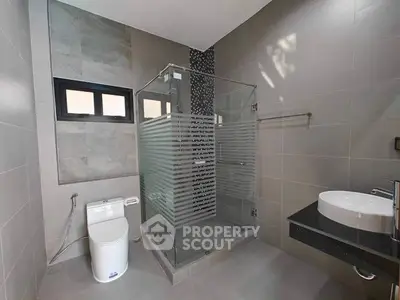Modern bathroom with glass shower enclosure and sleek fixtures in a contemporary home.