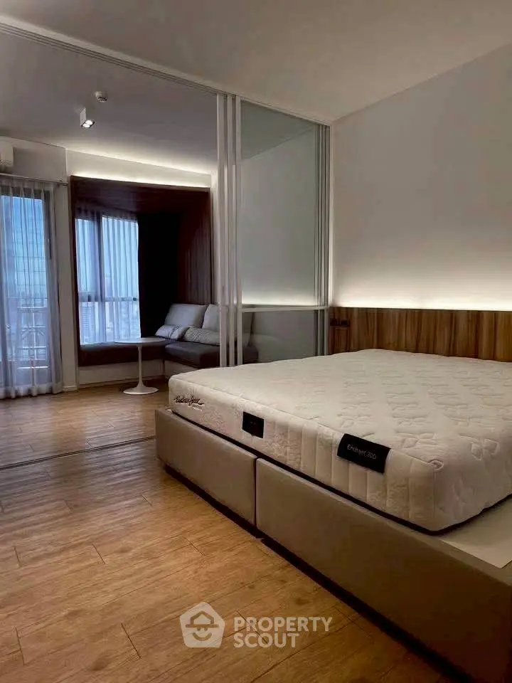 Modern bedroom with wooden flooring and large windows offering natural light.