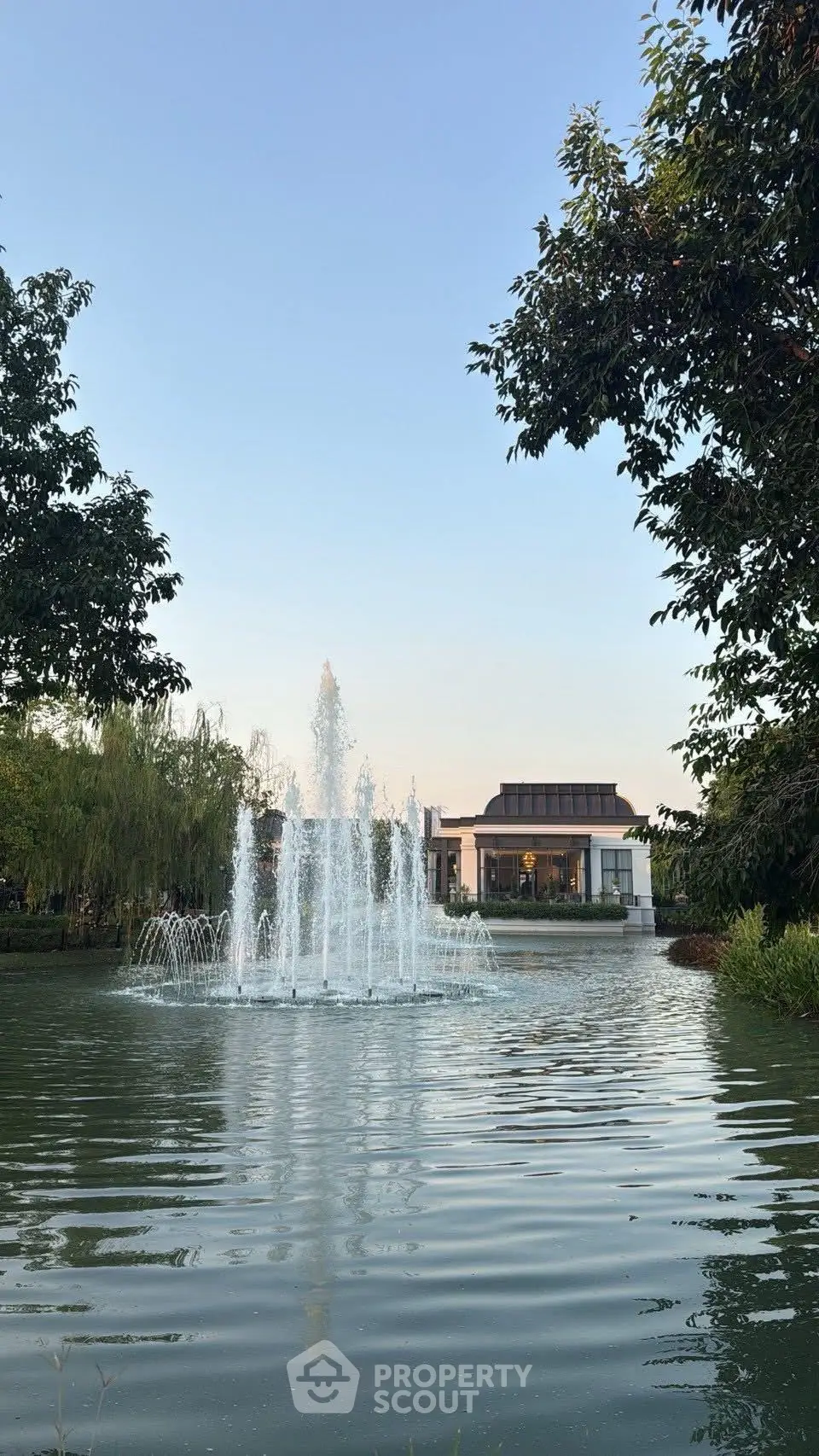 Stunning garden view with elegant fountain and modern building backdrop.