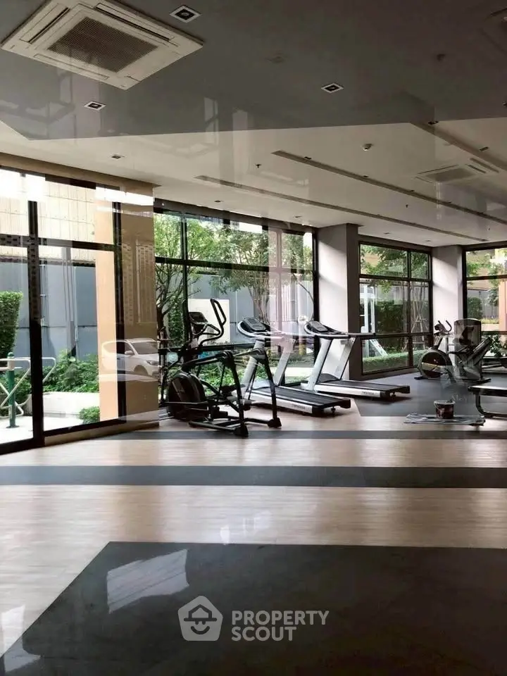 Modern gym with large windows and fitness equipment in a luxury residential building.