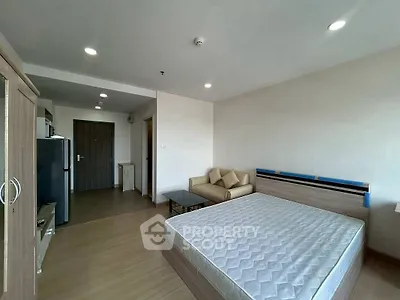 Spacious modern bedroom with wooden flooring and cozy seating area.