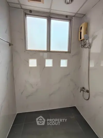 Minimalist bathroom with marble walls and modern shower fixtures