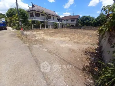 Vacant land plot in a residential area with clear blue sky, ideal for new construction.