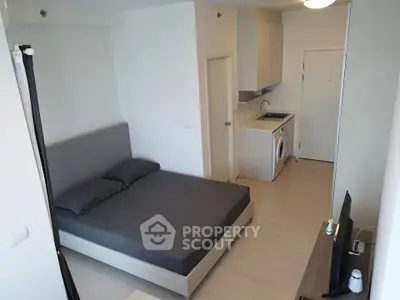 Modern studio apartment with sleek design and integrated kitchen appliances.