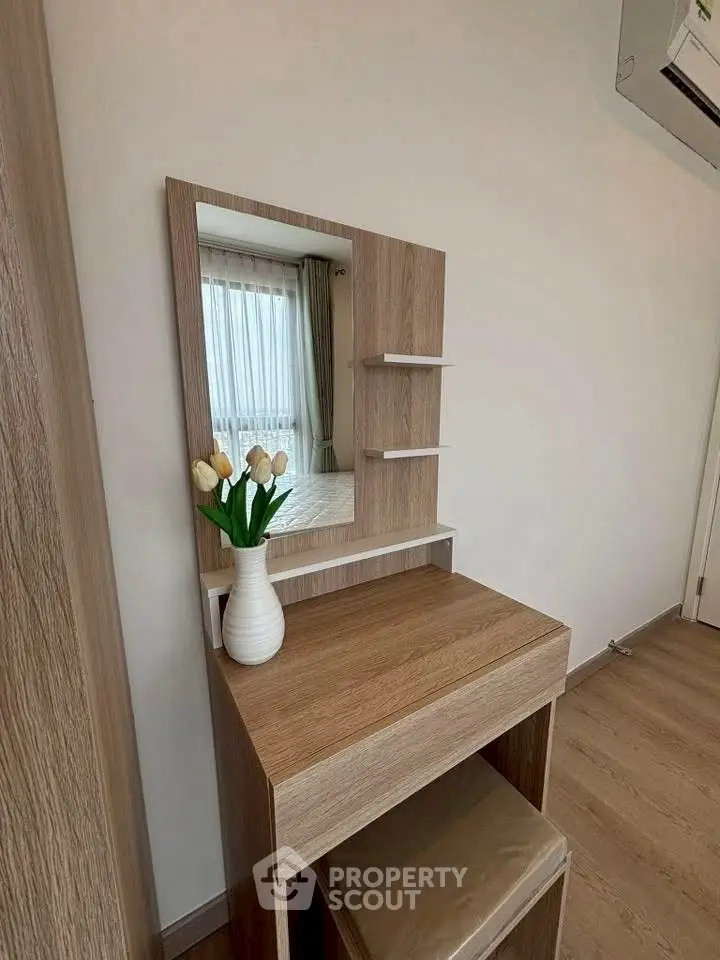 Elegant bedroom corner with wooden vanity and mirror, featuring a vase of tulips and natural light.