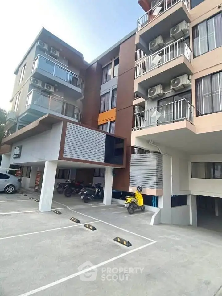 Modern apartment building with balconies and parking area, showcasing urban living convenience.
