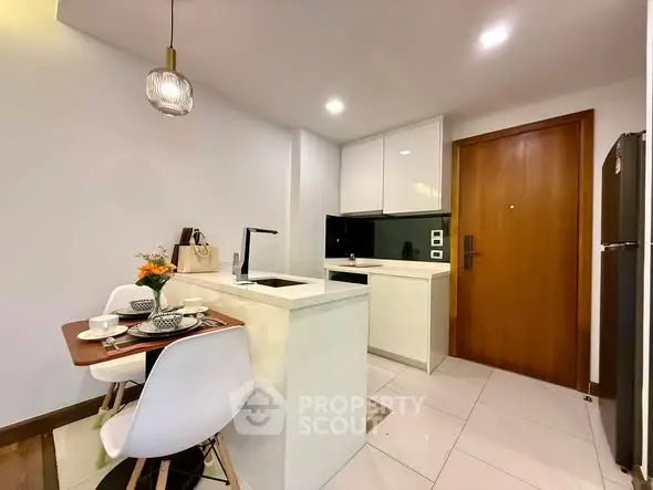 Modern kitchen with sleek design and dining area, featuring white cabinetry and stylish lighting.