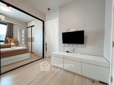 Modern bedroom with sleek design, featuring a wall-mounted TV and mirrored closet doors.