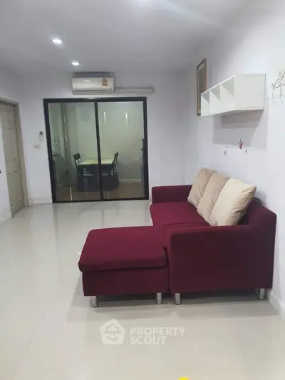 Spacious living room with modern red sofa and dining area view