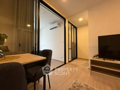 Modern living room with glass partition, dining area, and air conditioning in a cozy apartment.