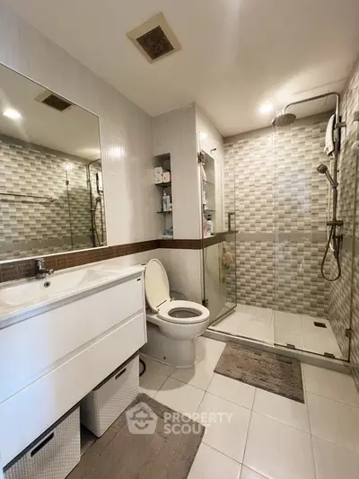 Modern bathroom with glass shower and sleek vanity in contemporary home.