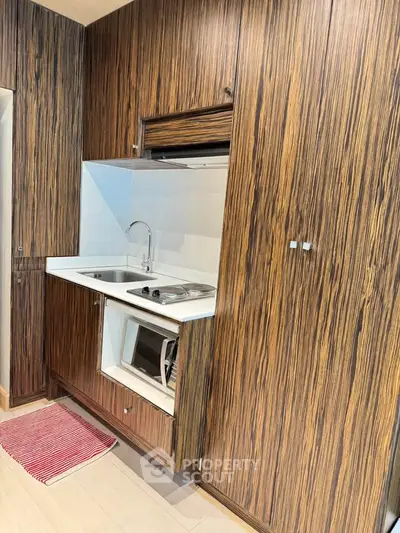 Modern compact kitchen with wood paneling and built-in appliances