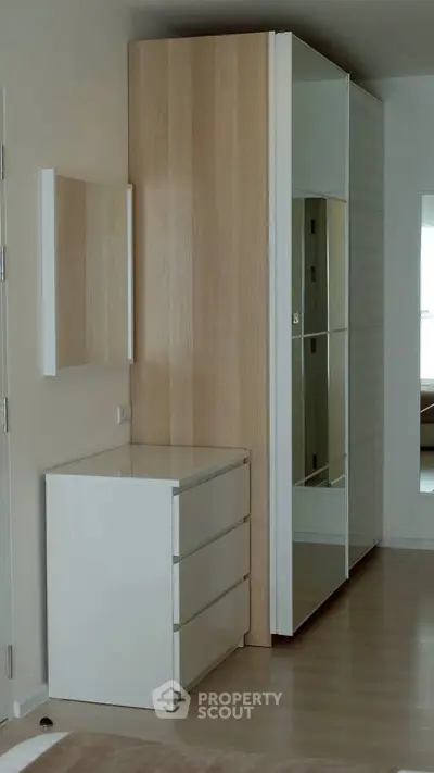 Modern bedroom with sleek wardrobe and dresser, featuring minimalist design and ample storage space.