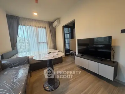 Modern living room with sleek furniture and large window offering natural light.