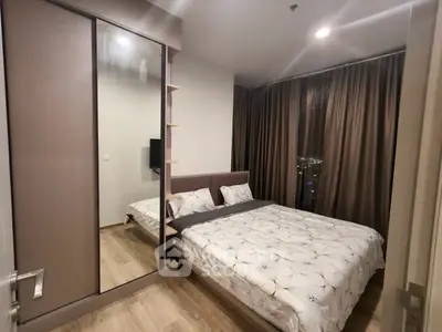 Modern bedroom with stylish decor and city view, featuring a cozy bed and mirrored wardrobe.