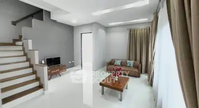 Modern living room with sleek staircase and cozy seating area