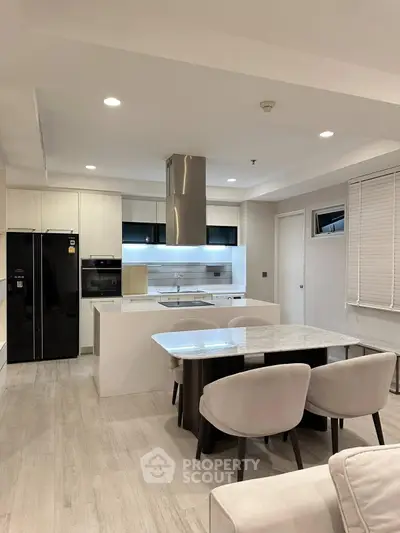 Modern kitchen with sleek design, featuring an open layout, dining area, and high-end appliances.
