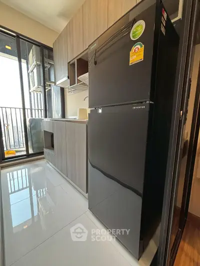 Modern kitchen with sleek black fridge and balcony view, perfect for urban living.