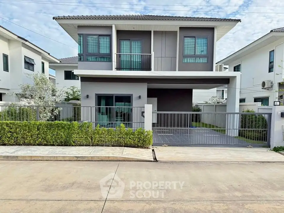 Modern two-story house with sleek design and spacious driveway in a suburban neighborhood.