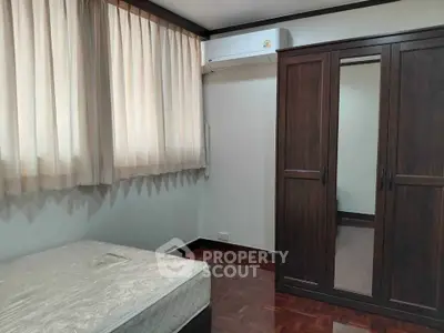 Cozy bedroom with air conditioning and wooden wardrobe, perfect for comfortable living.