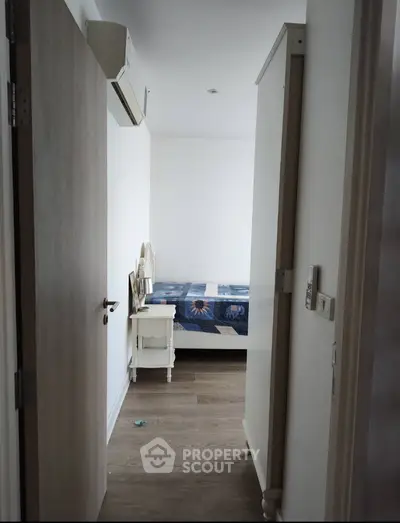 Cozy bedroom with wooden flooring and air conditioning, perfect for a comfortable living experience.