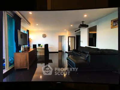 Spacious modern living room with sleek black leather sofa and large TV, perfect for entertainment.